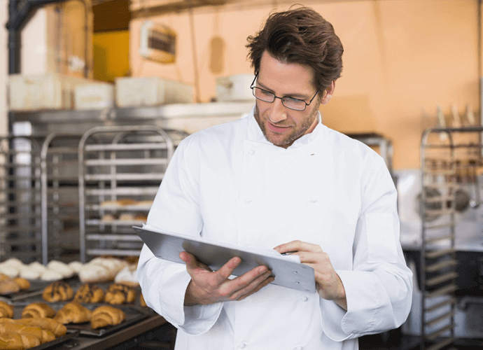 Healthcare chef looking at a tablet in a kitchen