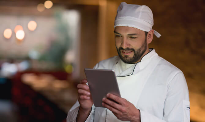 Healthcare chef looking at a tablet in a kitchen