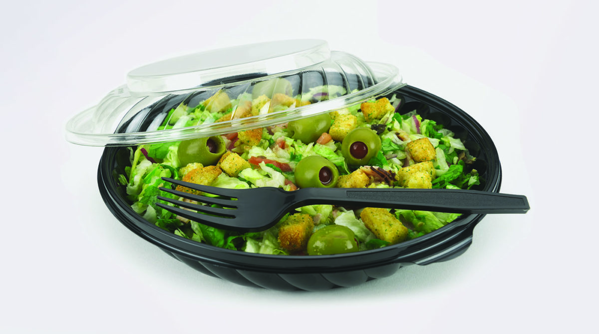 Salad featuring greens, olives and croutons is set in a to-go container.